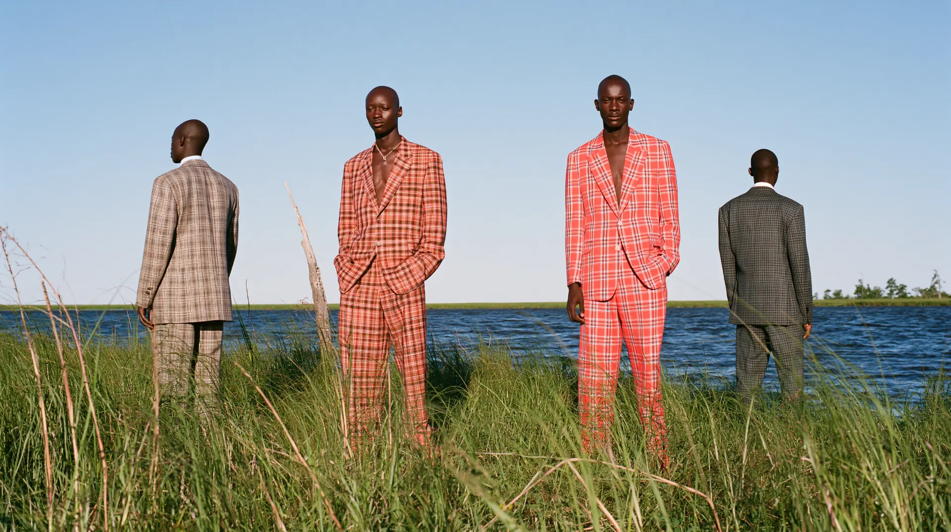 Editorial campaign photograph of four men in plaid suits by a lake